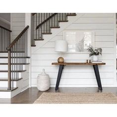 a room with white walls and wood floors has a rug on the floor next to a wooden table