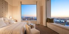 a bedroom with a large window and a view of the city from it's floor to ceiling windows