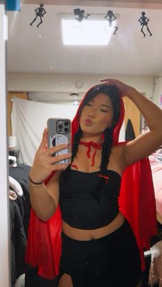 a woman taking a selfie in a mirror with her cell phone and red cape