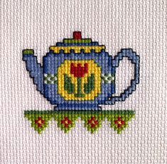 a cross stitch picture of a blue teapot