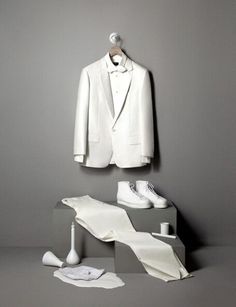 a white suit sitting on top of a table next to a pair of shoes and an object