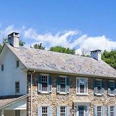 an old stone house with blue shutters on the front and windows in the back