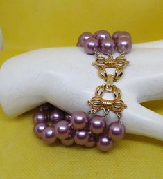 Never Worn Vintage triple strand Marvella lavender purple colored knotted faux pearl bracelet with an ornate gold-tone metal clasp. All 3 sections of the gold tone clasp are signed Marvella. Length including clasp 8 & 1/4 inches. Width 1 & 1/8 inches. I offer multiple-item-order shipping discounts. Pearl Jewelry Design, Faux Pearl Bracelet, Pearl Accessories, Purple Bracelet, Purple Pearl, Pretty Bracelets, Strand Bracelet, Vintage Pearls