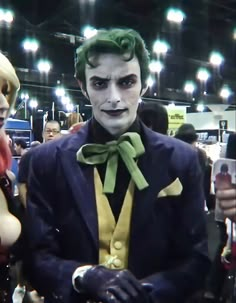 a man in a suit and bow tie standing next to another person with green hair