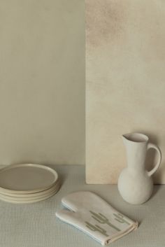 a white vase sitting on top of a table next to two plates and a napkin