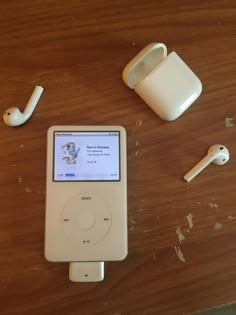 an ipod sitting on top of a wooden table next to ear buds and headphones