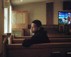 a young man sitting in the pews of a church looking off into the distance