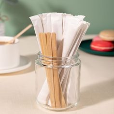 several wooden sticks in a glass jar on a table next to a cup and plate