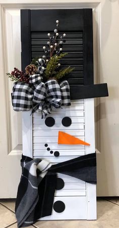 a snowman door hanger made out of an old shutter and some black and white fabric