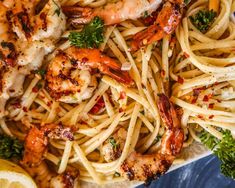 pasta with shrimp, parsley and lemon wedges on a plate