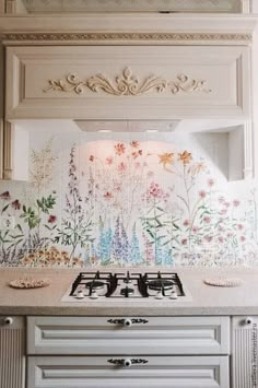 a white stove top oven sitting next to a wall with flowers painted on the side