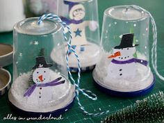 three snowmen under glass bell jars on a table