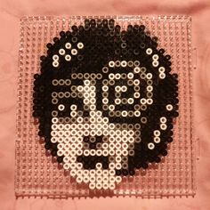 a black and white beaded skull on a pink background