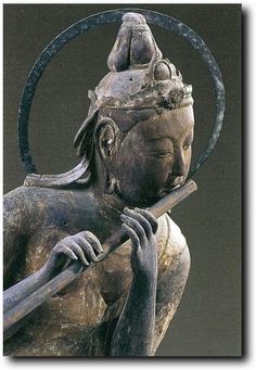 an old statue holding a stick and wearing a crown on top of it's head