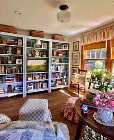 a living room filled with lots of furniture and bookshelves next to a window