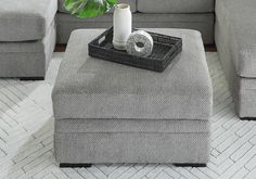 a living room with grey couches and a white rug on the floor, coffee table