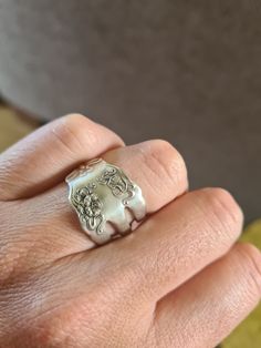 a person's hand with a silver ring on top of their finger and an elephant head in the middle