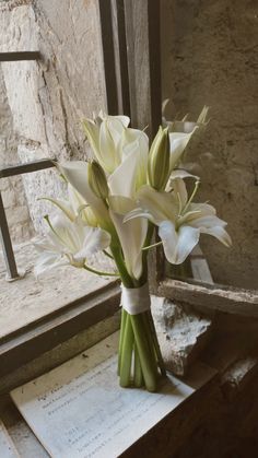 a bouquet of white flowers sitting on top of a table next to a window sill