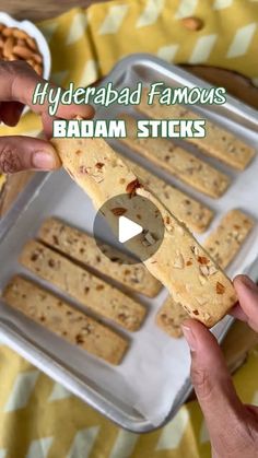 a person is holding a cracker in front of some food on a tray with the words, hyperad famous badam sticks