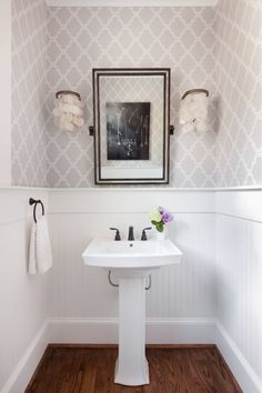 a white pedestal sink sitting under a mirror next to a wall mounted towel dispenser