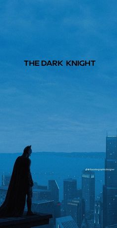 the dark knight is standing on top of a building looking out at the city below