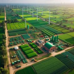 an aerial view of a farm with wind turbines in the background and green fields around it