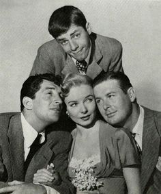 an old black and white photo of four people posing for the camera with one man leaning on his shoulder