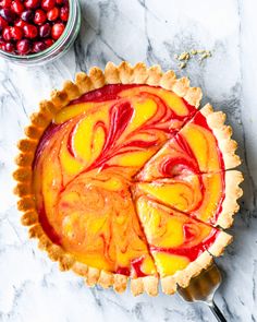 a pie sitting on top of a marble counter next to a bowl of cherries