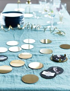 a table topped with lots of plates covered in gold and black circles on top of a blue cloth