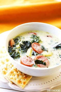 a white bowl filled with soup next to crackers