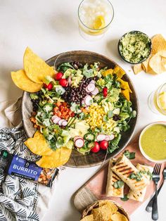 a salad with tortilla chips, salsa and guacamole on the side