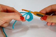 two hands are crocheting together with yarn