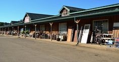 a row of shops on the side of a road with chairs and other items outside