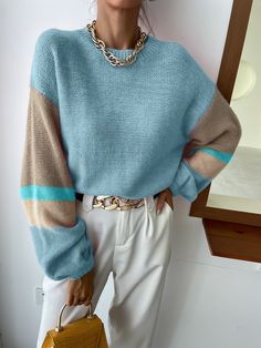 a woman wearing a blue sweater and white pants holding a yellow purse in front of a mirror