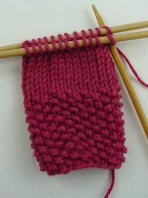 two knitting needles next to a red knitted object