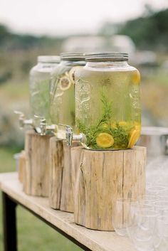 mason jars filled with lemonade and herbs sit on a table