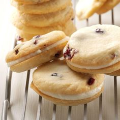 several cookies with white frosting and cranberries on a cooling rack