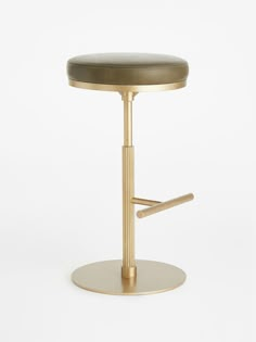 a gold stool with a black leather seat on a white background in front of a plain backdrop