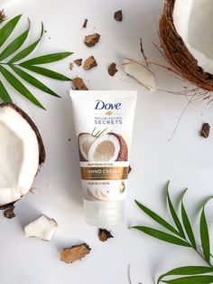 a tube of hand cream next to some coconuts on a white surface with leaves