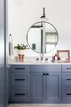 the bathroom is decorated in shades of blue and white, with an oval mirror over the sink