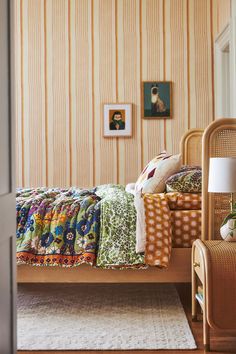 a bed sitting in a bedroom next to a chair and wall with pictures on it