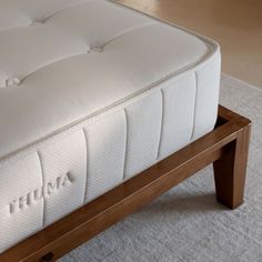 a close up of a mattress on a wooden bed frame in a room with white carpet