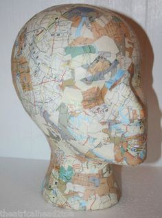 a white mannequin's head is covered in multicolored maps