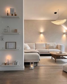 a living room with white furniture and candles on the shelves in front of the couch