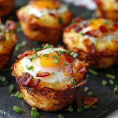 breakfast cups with bacon and an egg in them on a black tray, ready to be eaten