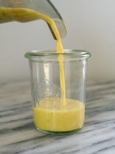 someone pouring orange juice into a glass jar