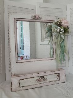 an old dresser with a mirror and flowers on it's front door, sitting on a bed