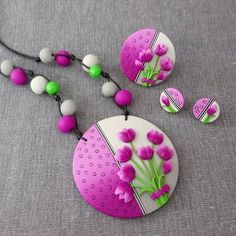 a necklace and earring set with pink flowers on the bead, along with matching beads