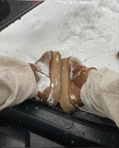 someone's feet covered in snow on top of a car