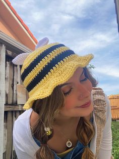 a woman wearing a yellow and black striped crochet hat with ear rings on her head